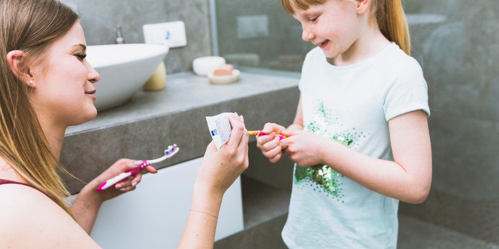 Matka dává dceři na kartáček zubní pastu.