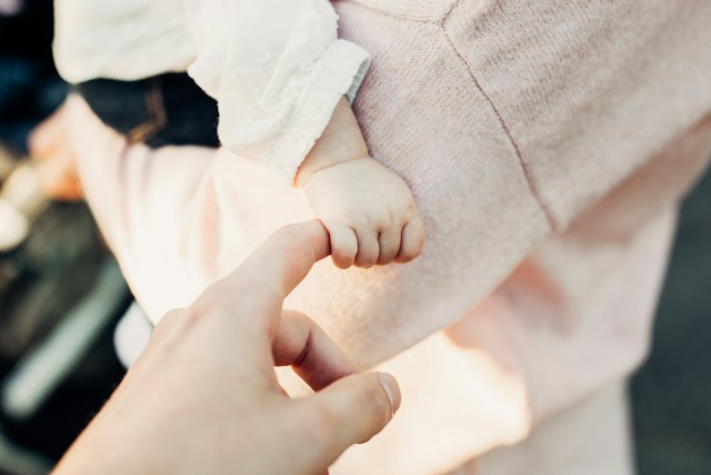 Dítě drží ruku rodiče.